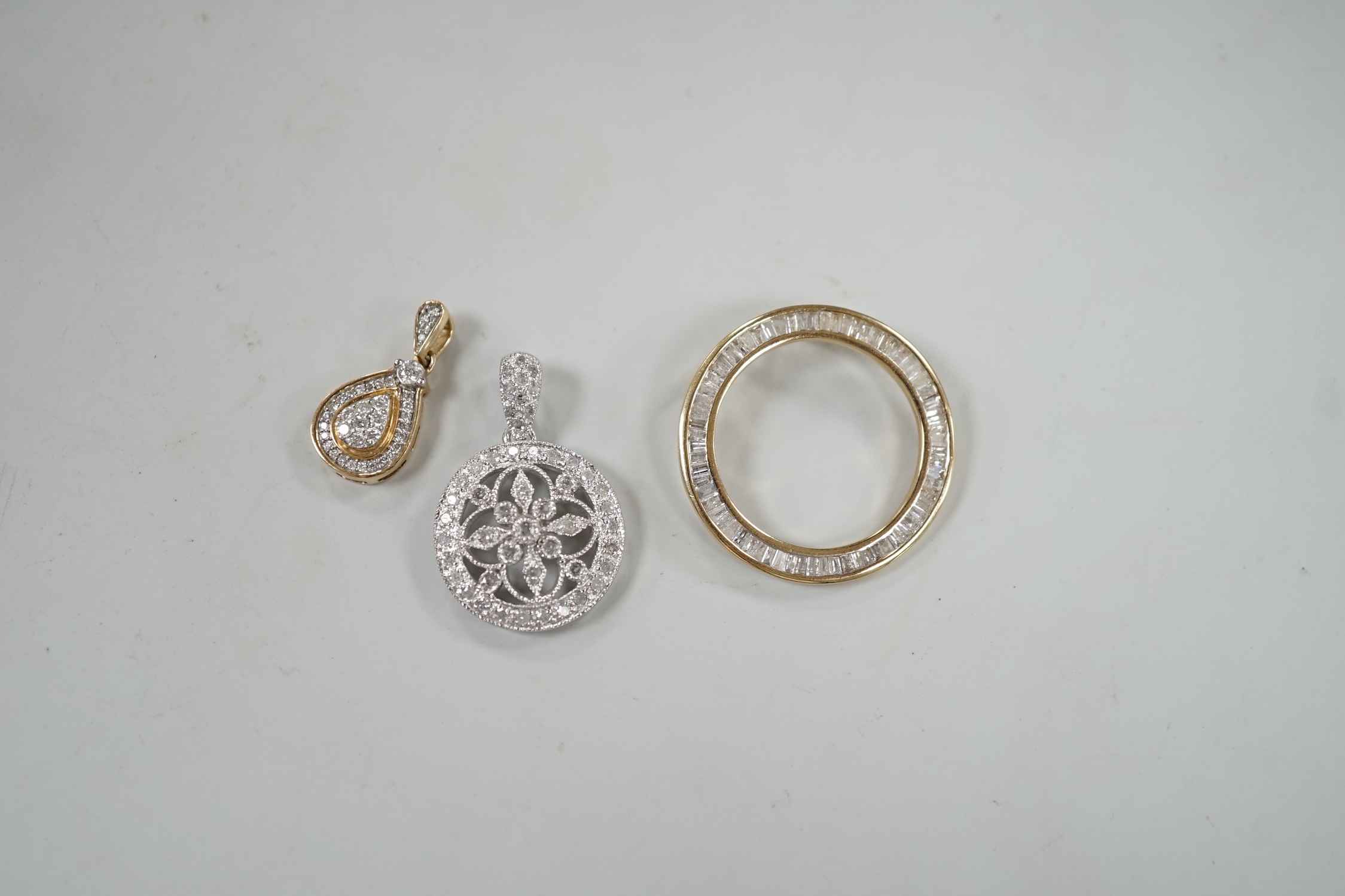 A modern 9ct white gold and diamond cluster set drop circular pendant, diameter 17mm, a small 9ct gold and diamond chip set pear shaped drop pendant and a 9ct gold and baguette cut diamond cluster set circular open work